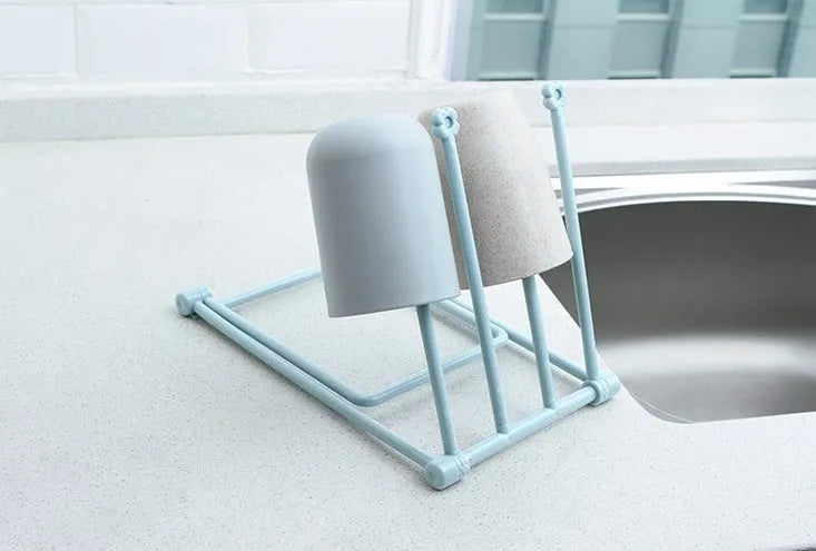 Light grey foldable plastic dishcloth shelf mounted on a wall holding towels.
