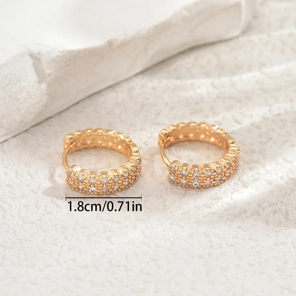 Close-up of women's copper geometric ear studs showing dot and ring pattern on a stud fitting.