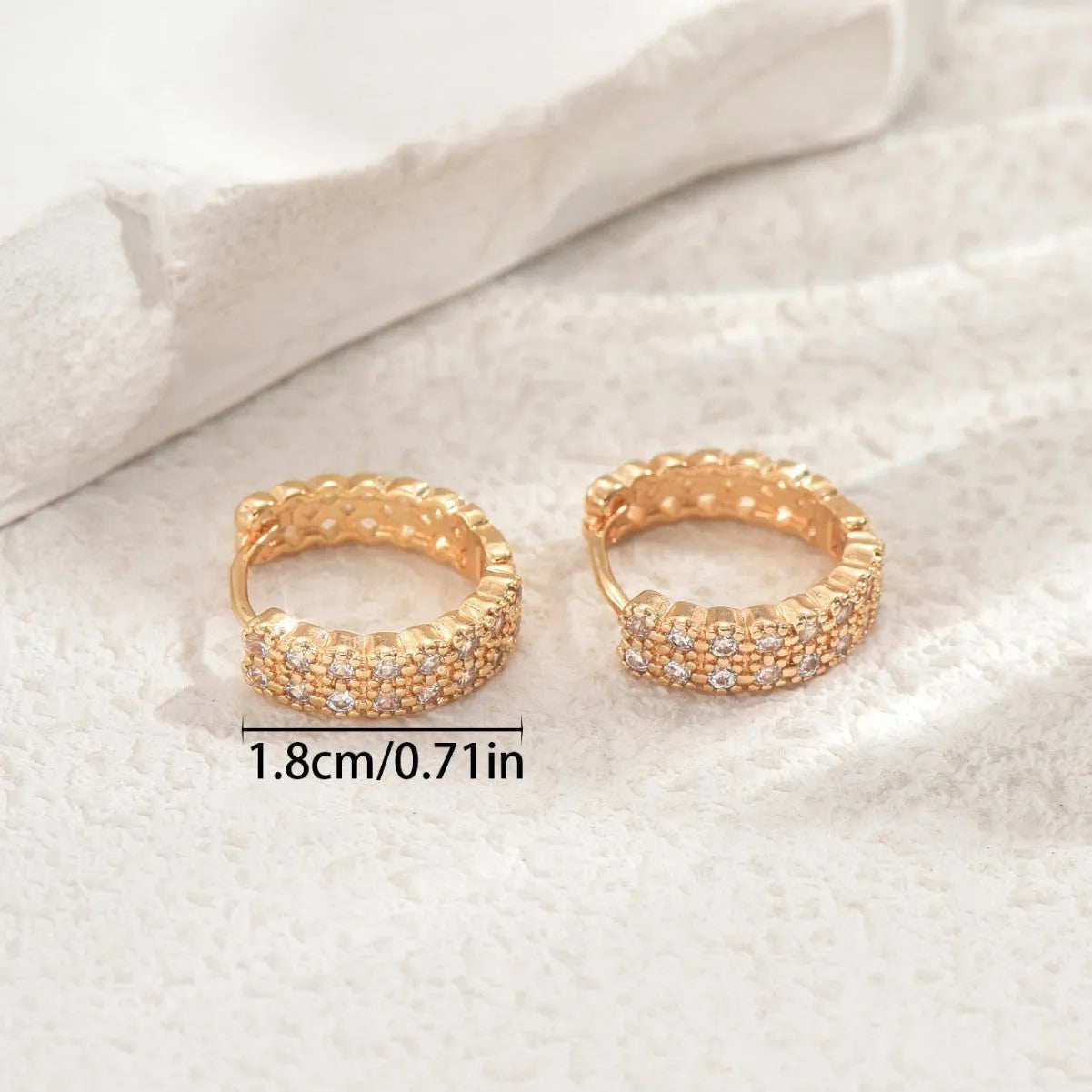 Close-up of women's copper geometric ear studs showing dot and ring pattern on a stud fitting.