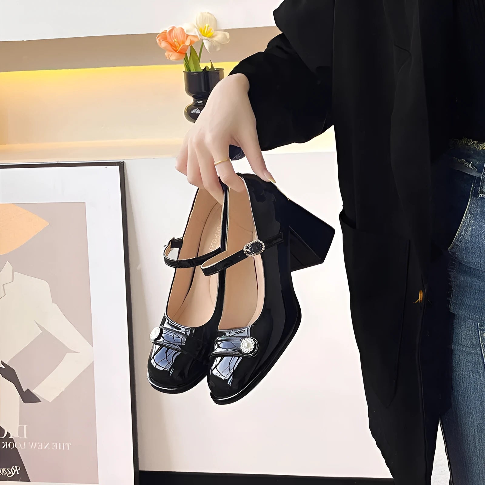 Women's black patent leather wide fit court shoes with a round toe and chunky buckle fastening heel.