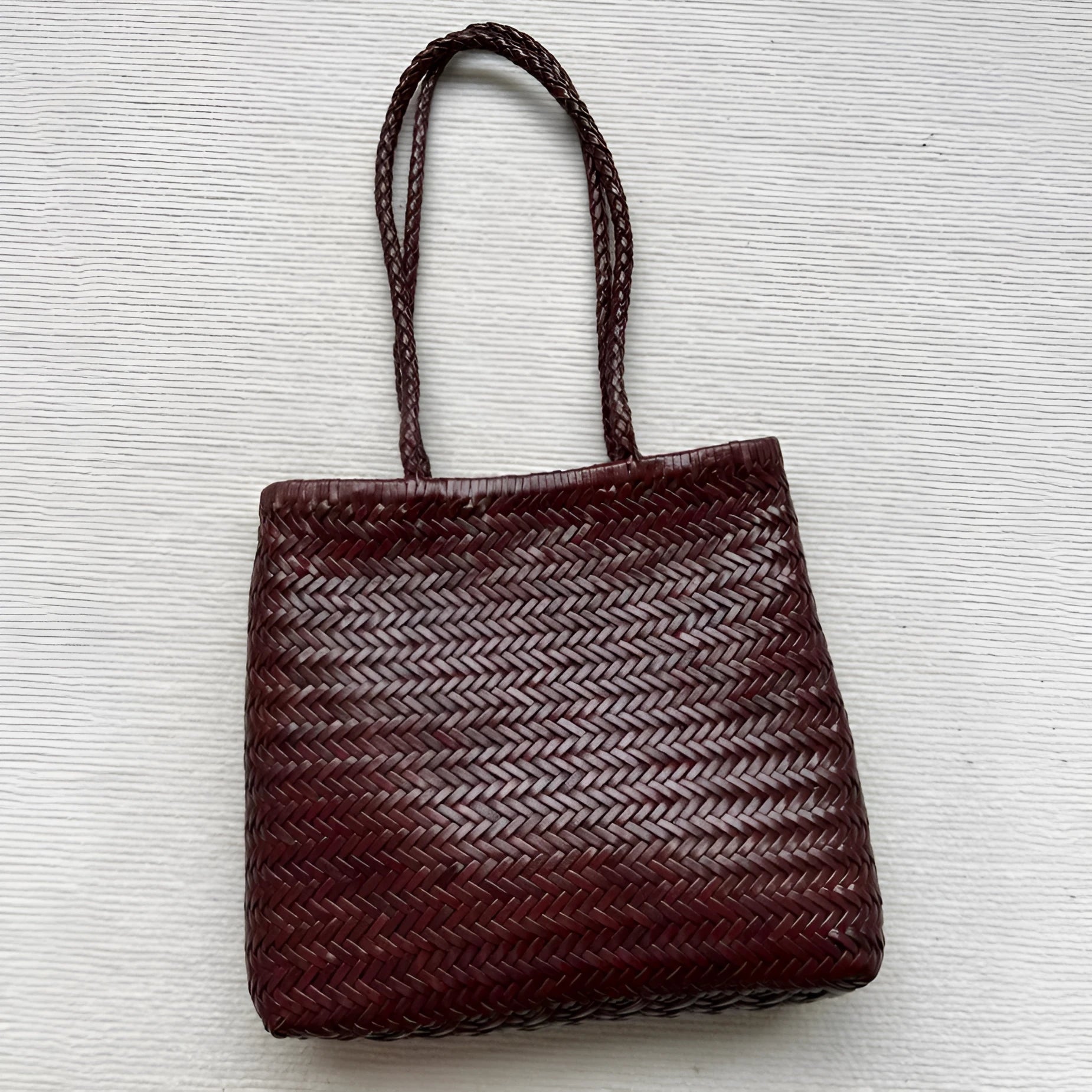 Brown handmade cowhide leather woven tote bag with a three-dimensional front pocket.