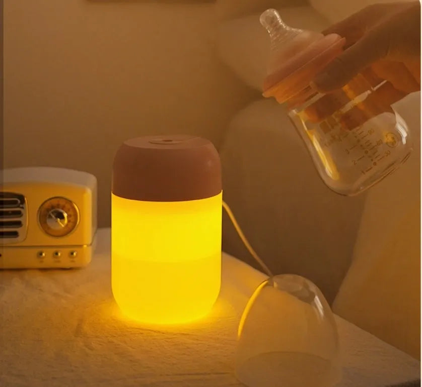 Small white cylindrical USB mini humidifier on a surface with its charging cable.
