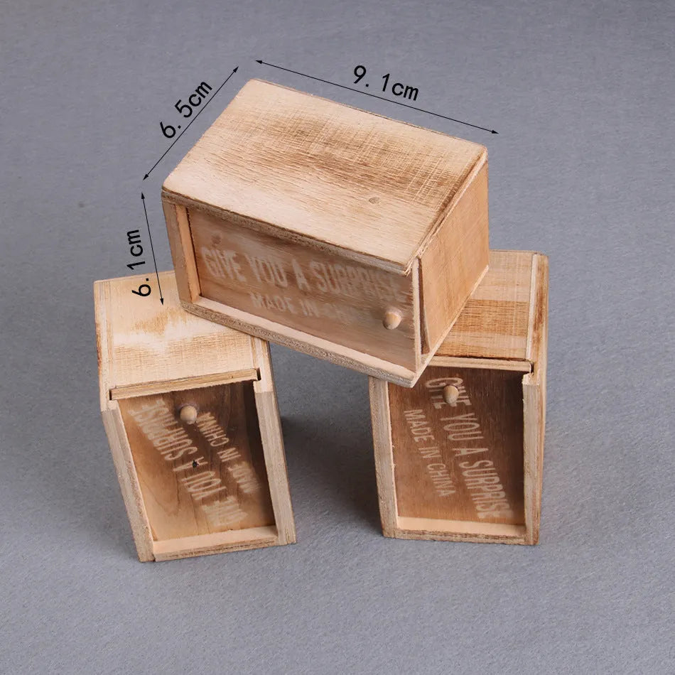 Wooden prank scare box with a lifelike spider figurine on a table.