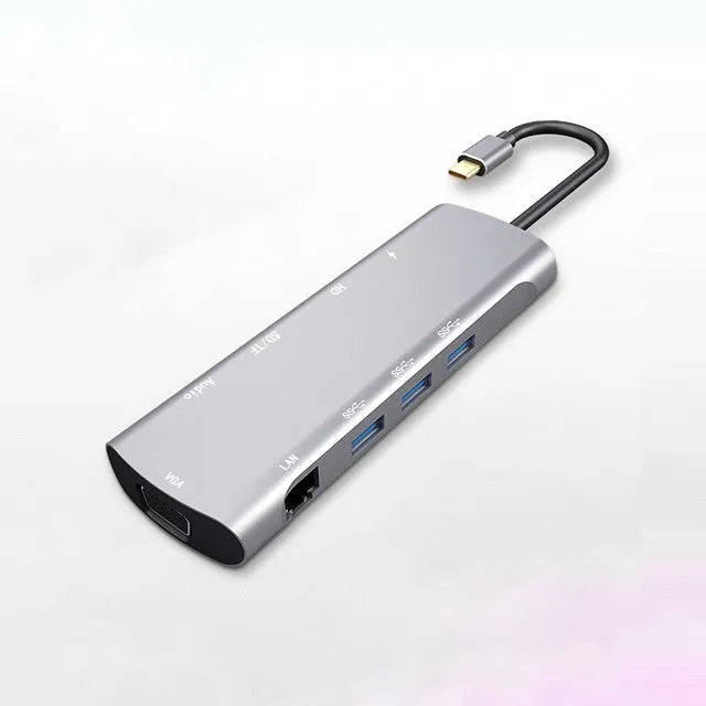 Grey aluminium USB-C docking station with multiple ports including HDMI, VGA, and USB, showing its 140mm attached cable.