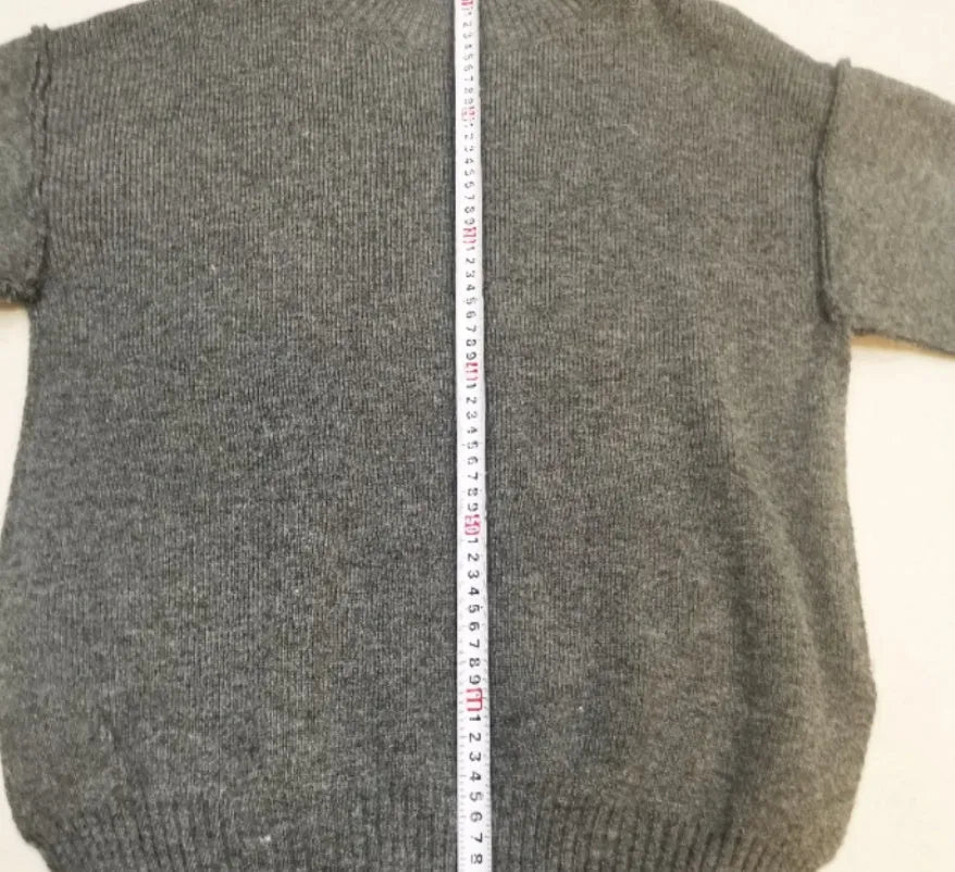 Women's dark grey acrylic knit suit with side-slit hem sweater and matching trousers laid flat.