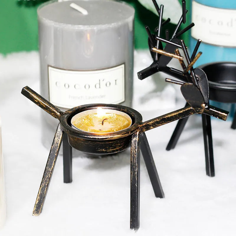 Black iron Christmas deer candlestick holder with elk silhouette on a table.