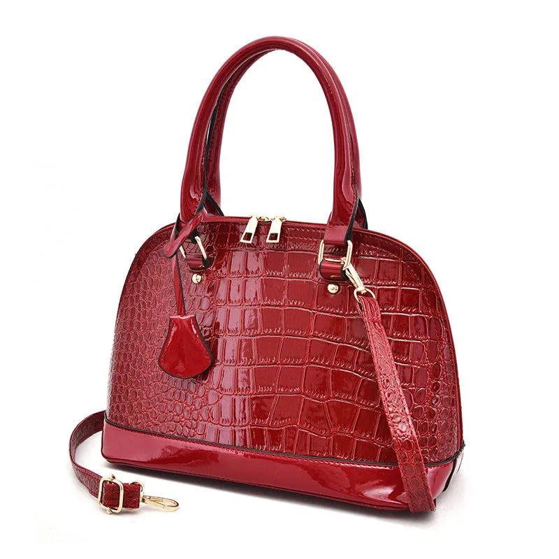 Women's large shiny PU leather crossbody shoulder bag in shell shape, shown in black colour.