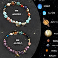 Close-up of two natural stone beaded bracelets with adjustable knots on a wooden surface, showing zodiac charm details.