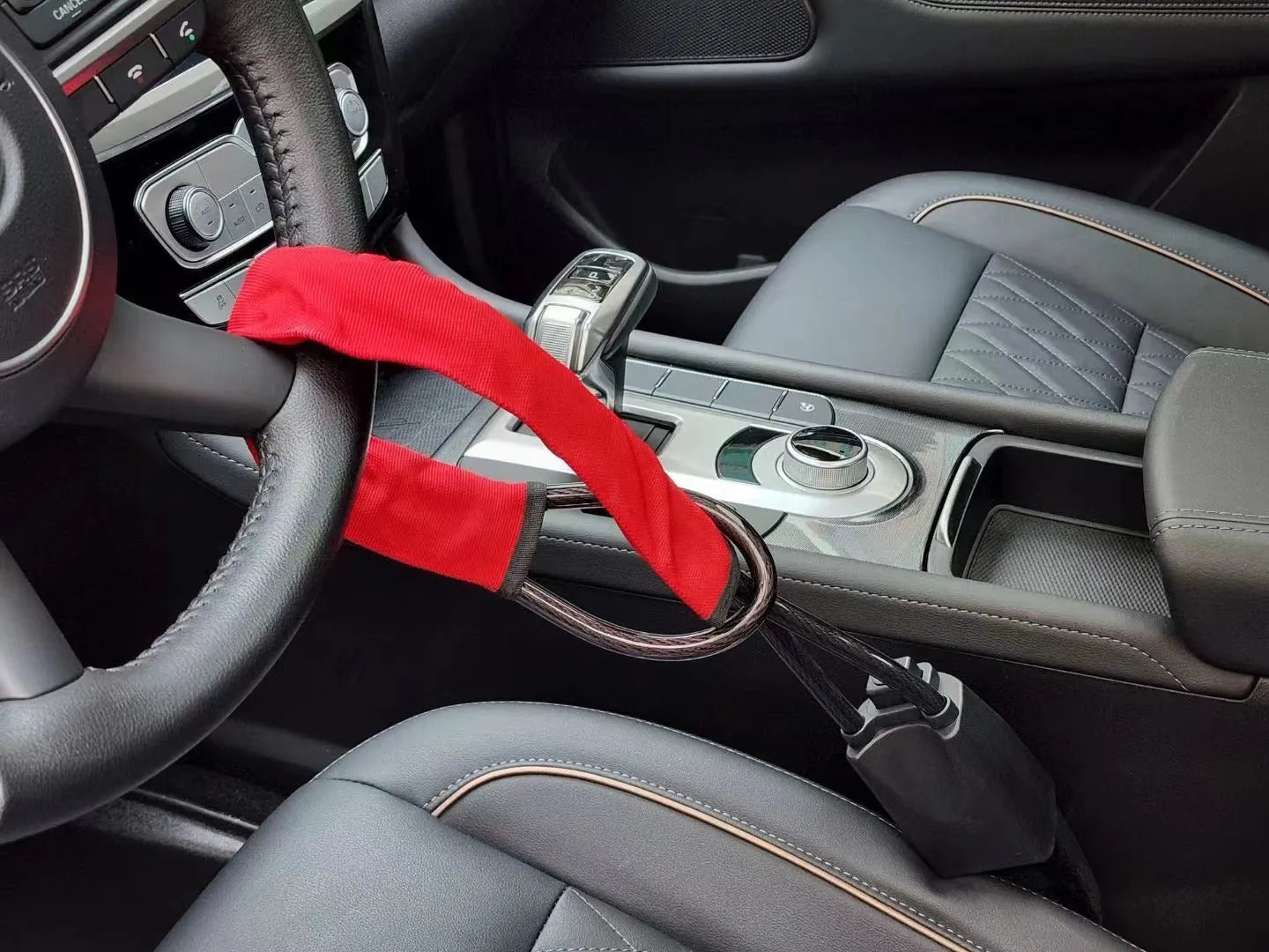 Red iron car steering wheel lock with brass core for General Motors vehicles on a steering wheel.