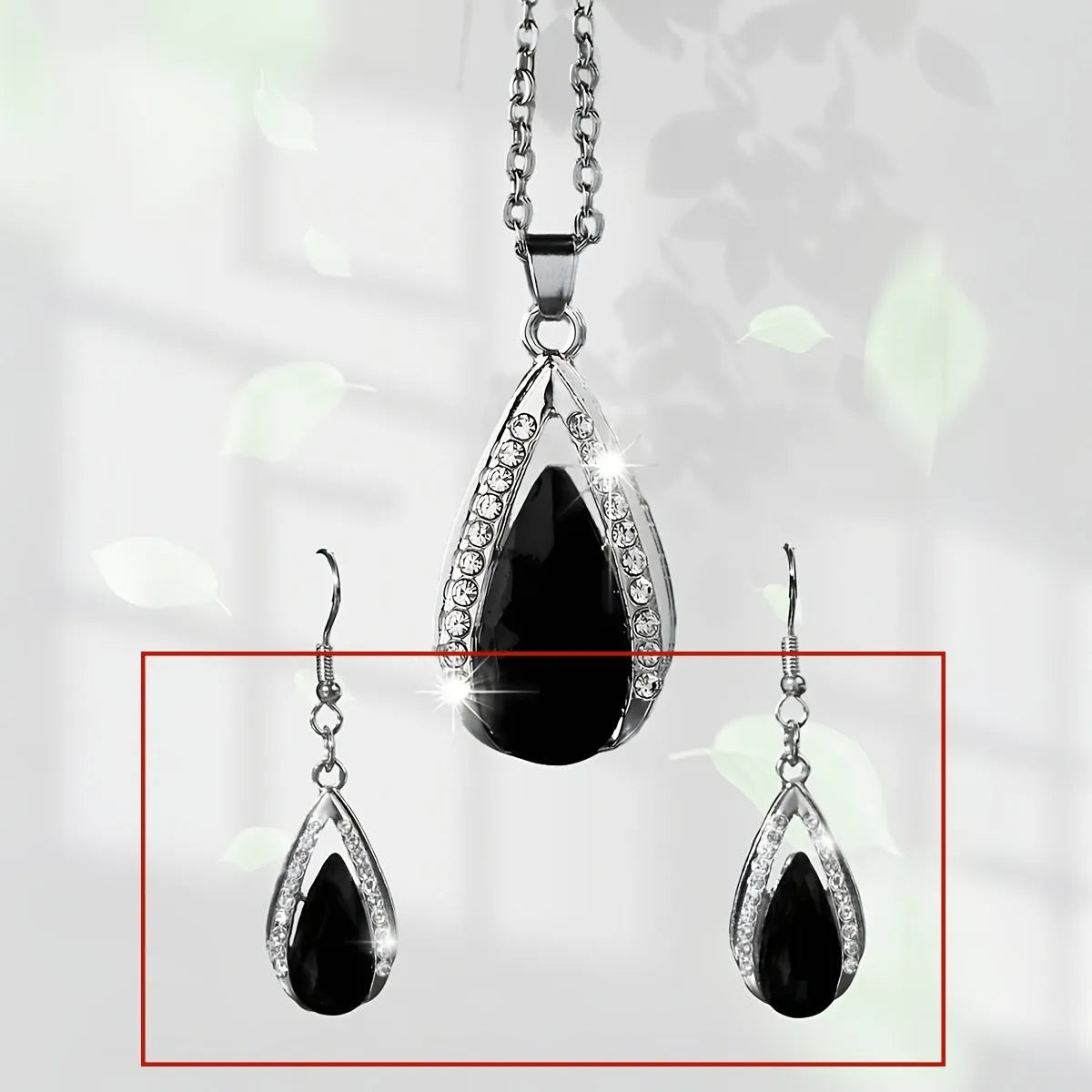 Black and red teardrop glass pendant necklace and matching earrings set on a grey background
