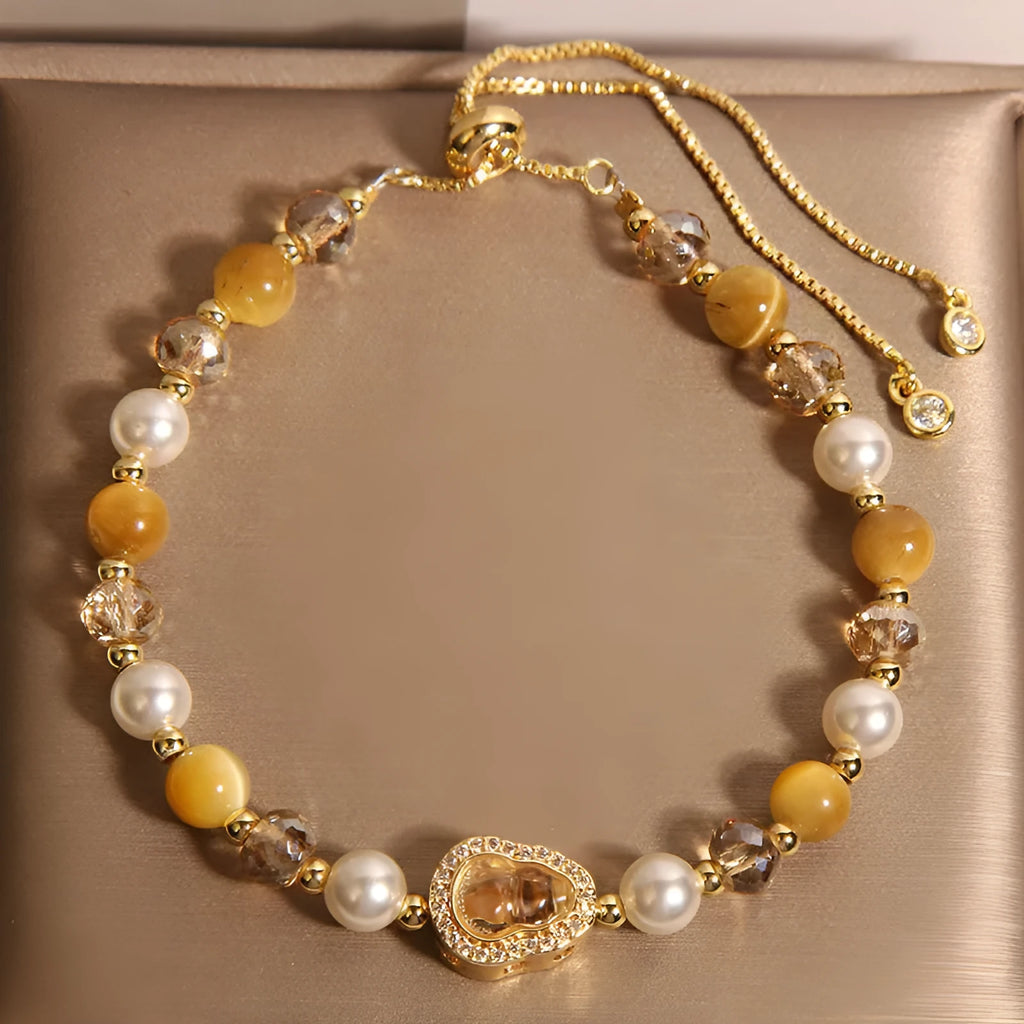 Yellow tiger's eye glass gourd pendant bracelet with alloy inlay and stone accents on a wrist.