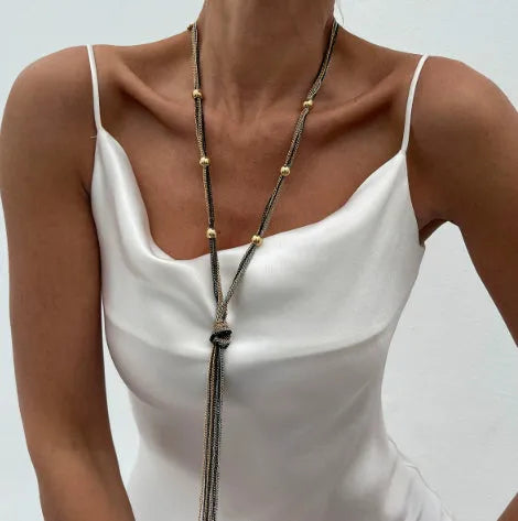 Simple Y-shaped metal tassel necklace in gold finish on a woman, with matching earrings, minimalist style for commuting wear