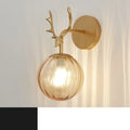 Round clear glass wall lamp with a minimalist design mounted on a light-coloured wall, emitting a soft, diffused warm white glow.