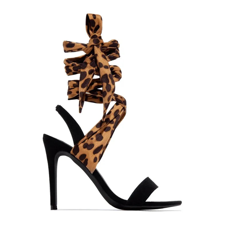 Light brown women's high heels with leopard print, thin ankle straps, and a tall stiletto heel on a plain background.