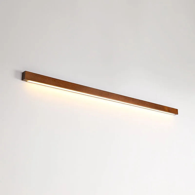 Walnut-coloured minimalist log strip wall lamp mounted on a wall.