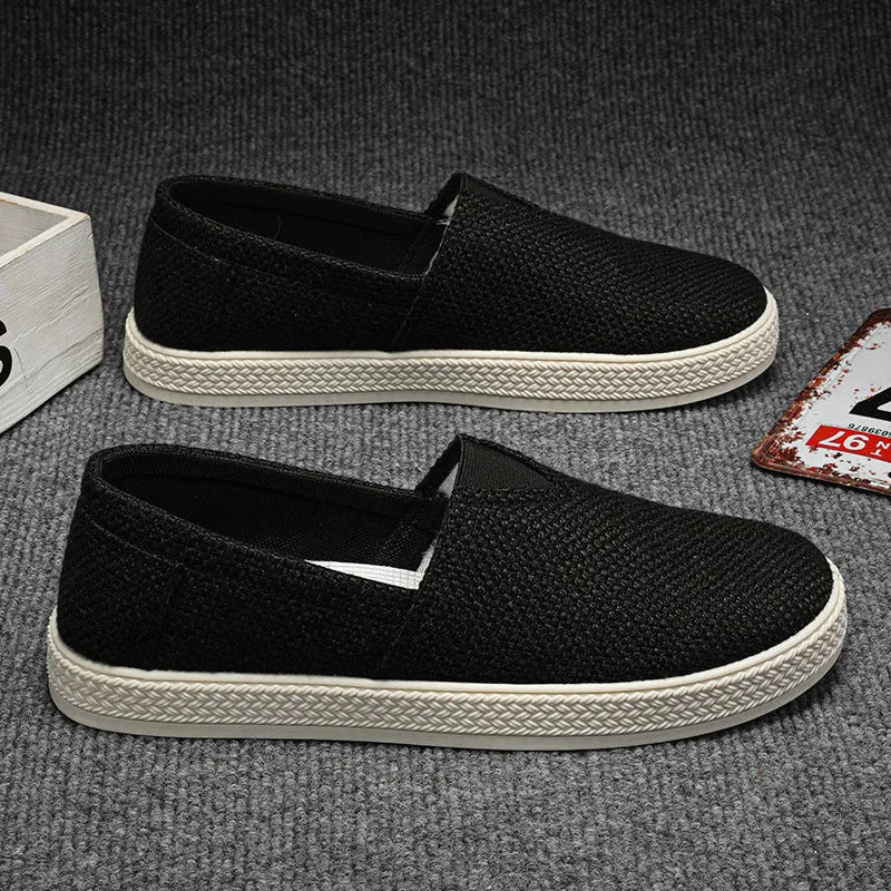 Men's beige linen cloth slip-on shoes with a round toe and shallow mouth on a grey background.