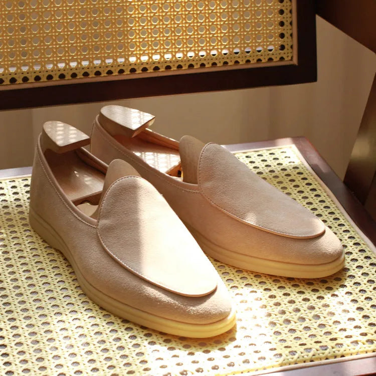 British handmade brown leather men's loafers with a flat TPR sole on a wooden surface.