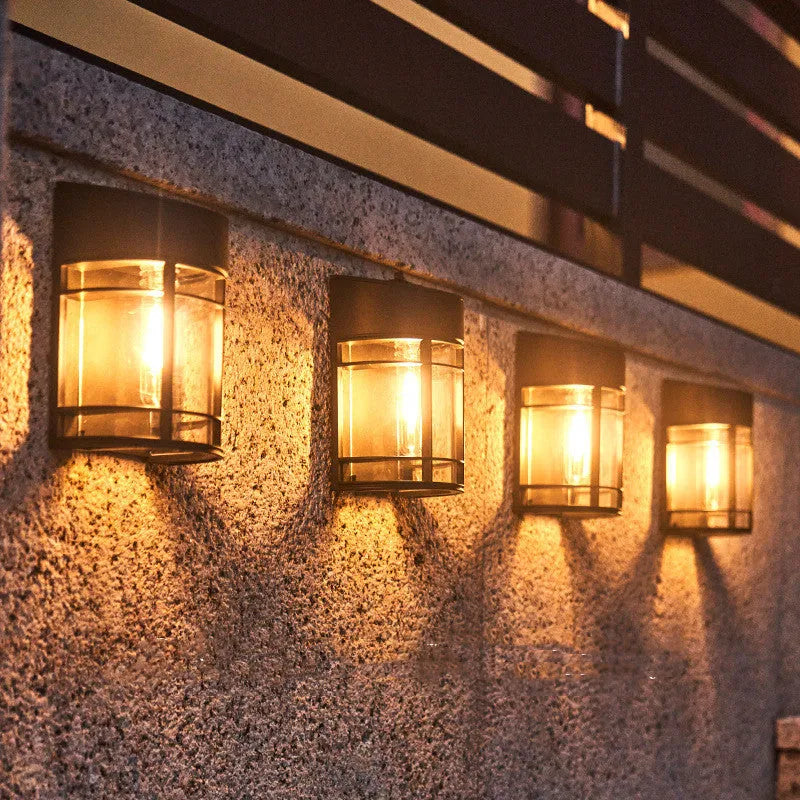 Small solar-powered outdoor wall light with warm white glow, mounted on an exterior wall.
