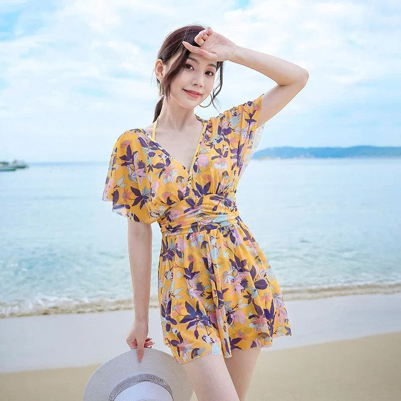 Yellow floral print women's one-piece swimsuit with skirted design.