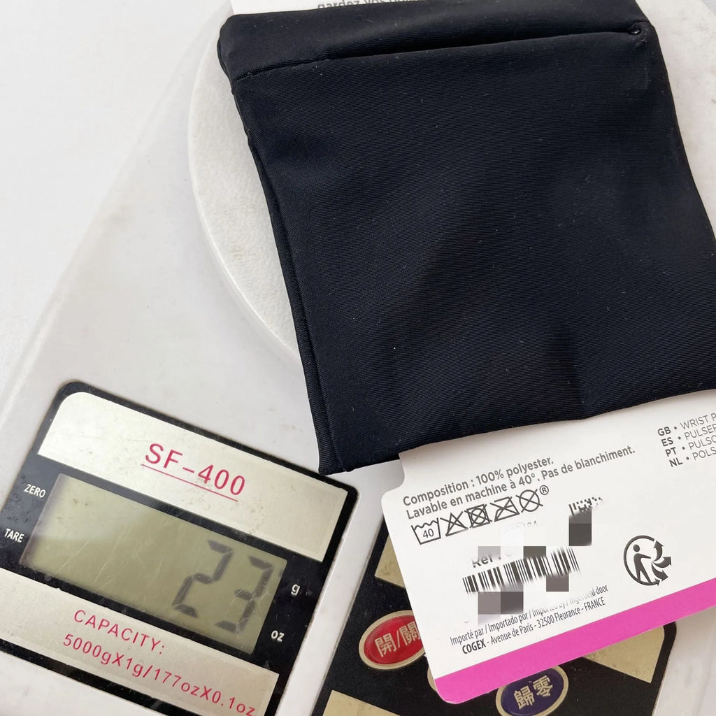 Black adjustable wrist bag with armband, showing zipped main compartment and external card slot on a person's forearm.