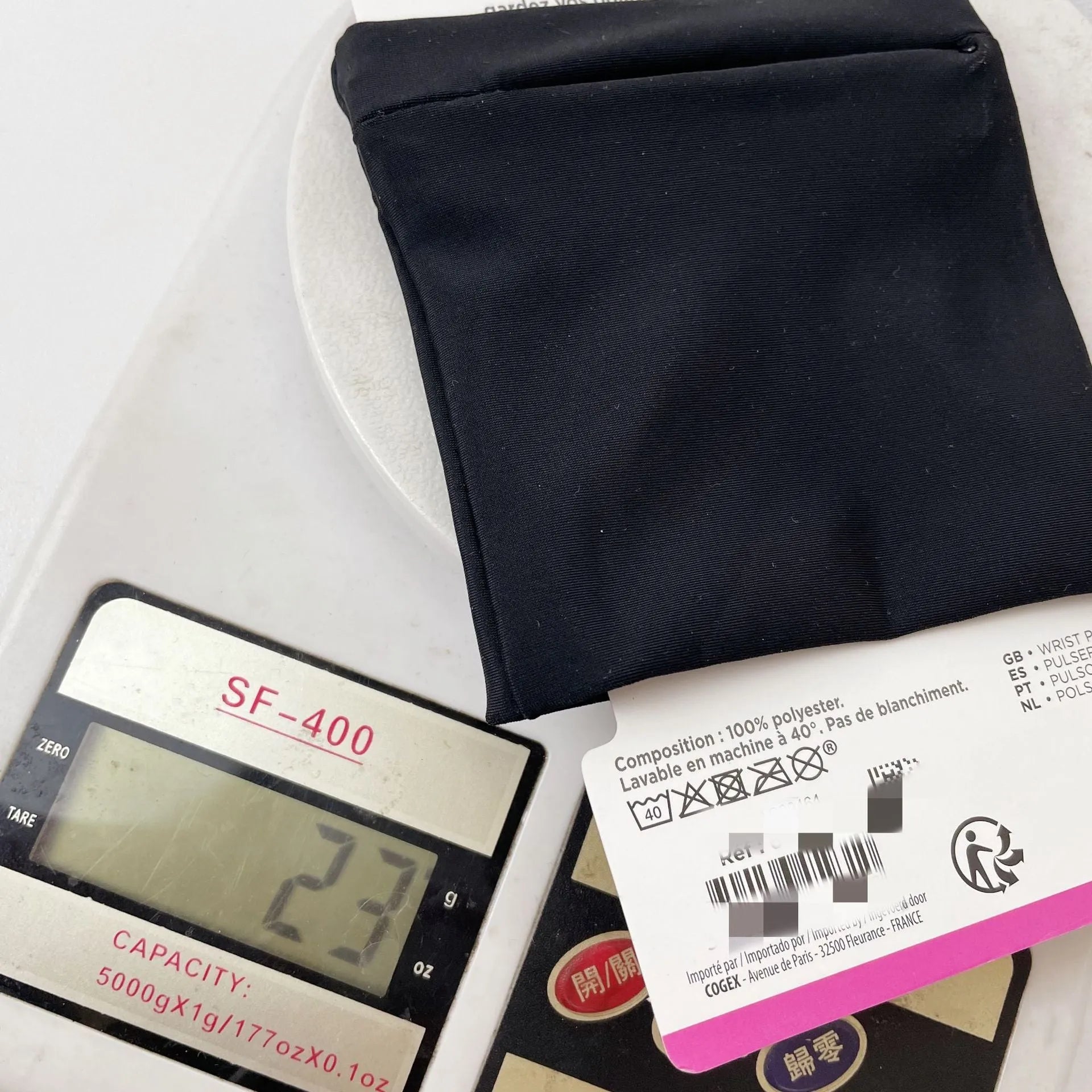 Black adjustable wrist bag with armband, showing zipped main compartment and external card slot on a person's forearm.