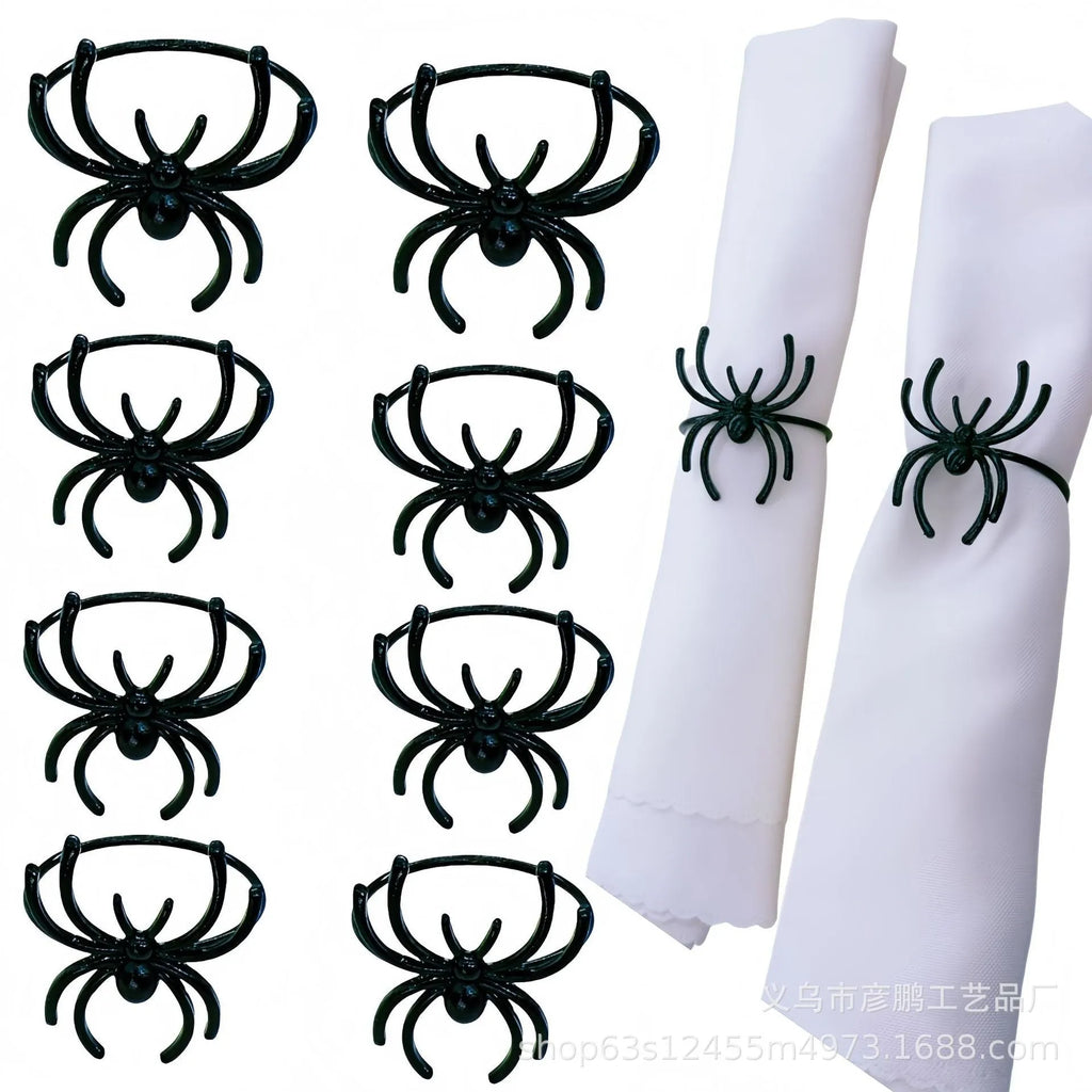 Six black alloy spider-shaped napkin rings for Halloween table decoration on a dark tablecloth.