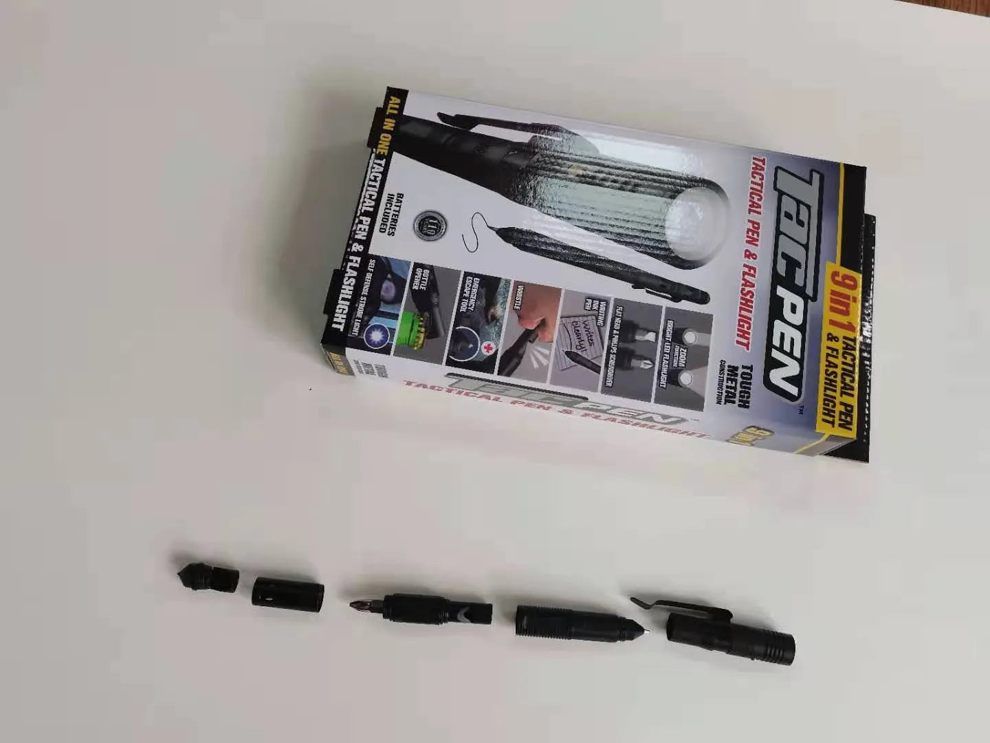 Black multi-function survival pen with built-in LED flashlight and pointed steel window breaker tip.