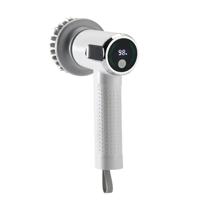 White cordless electric cleaning brush with interchangeable heads on a kitchen counter.