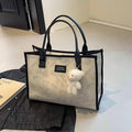 Women's black canvas tote bag with diamond pattern showing horizontal square shape and pendant attachment option