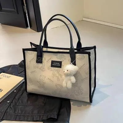 Women's black canvas tote bag with diamond pattern showing horizontal square shape and pendant attachment option