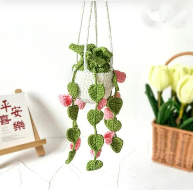 Green and white knitted wool car plant ornament hanging from a rope
