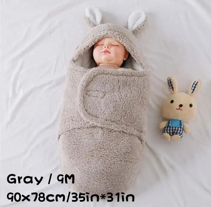 Baby wearing a grey adjustable fleece swaddle sleep sack with velcro wings
