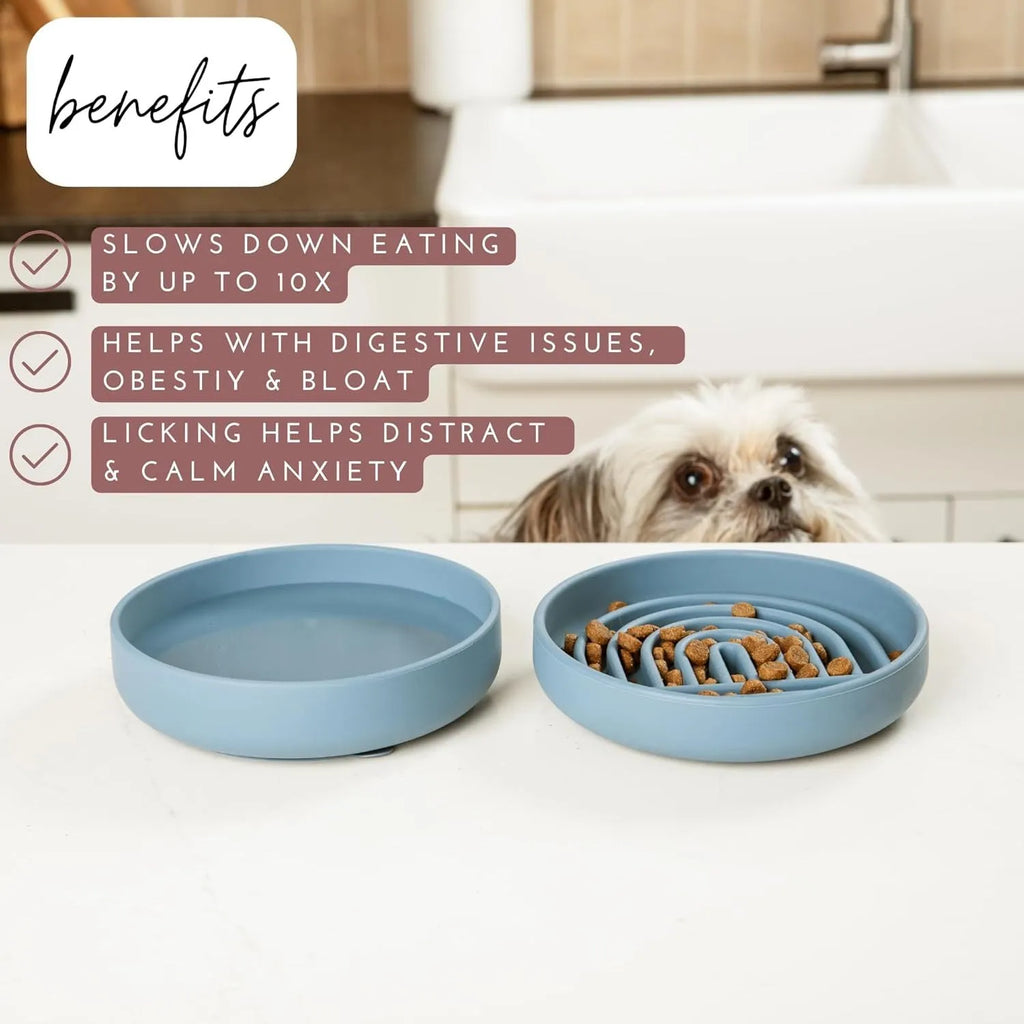 Beige silicone dog slow feeder bowl with ridges, shown next to a grey blue version on a wooden floor.