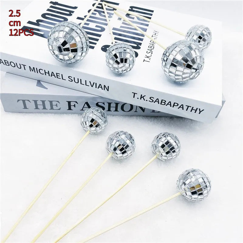 Glass disco ball cake decoration on a wooden stick in various sizes on a cake.
