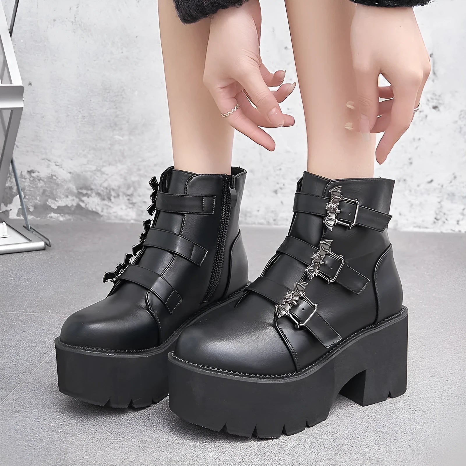 Black women's ankle boots with bat buckle, side zip, and thick heel.
