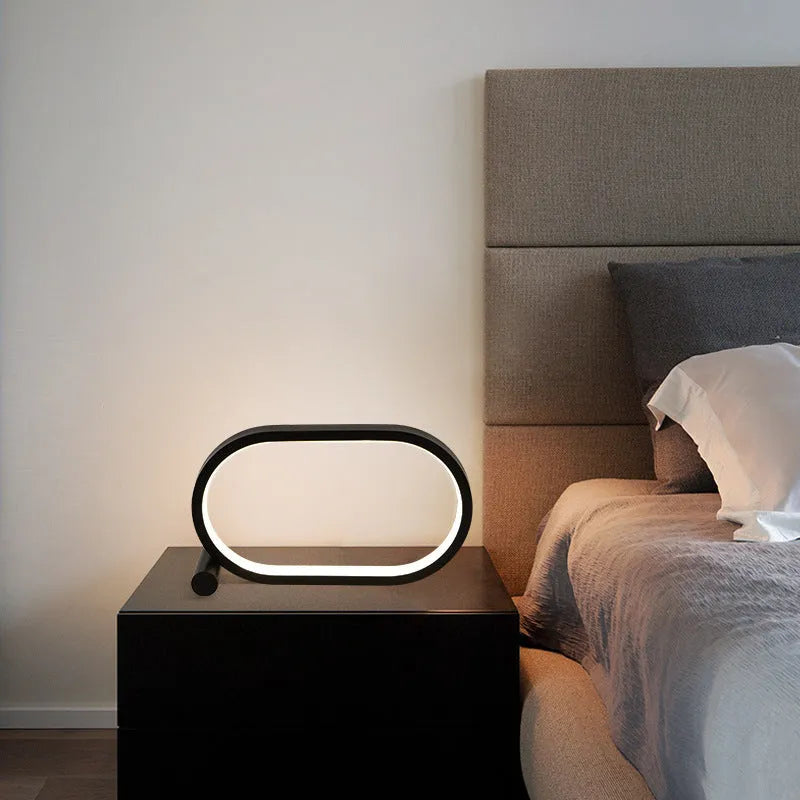 USB plug-in oval acrylic touch dimmable night light with metal base on a desk, black colour