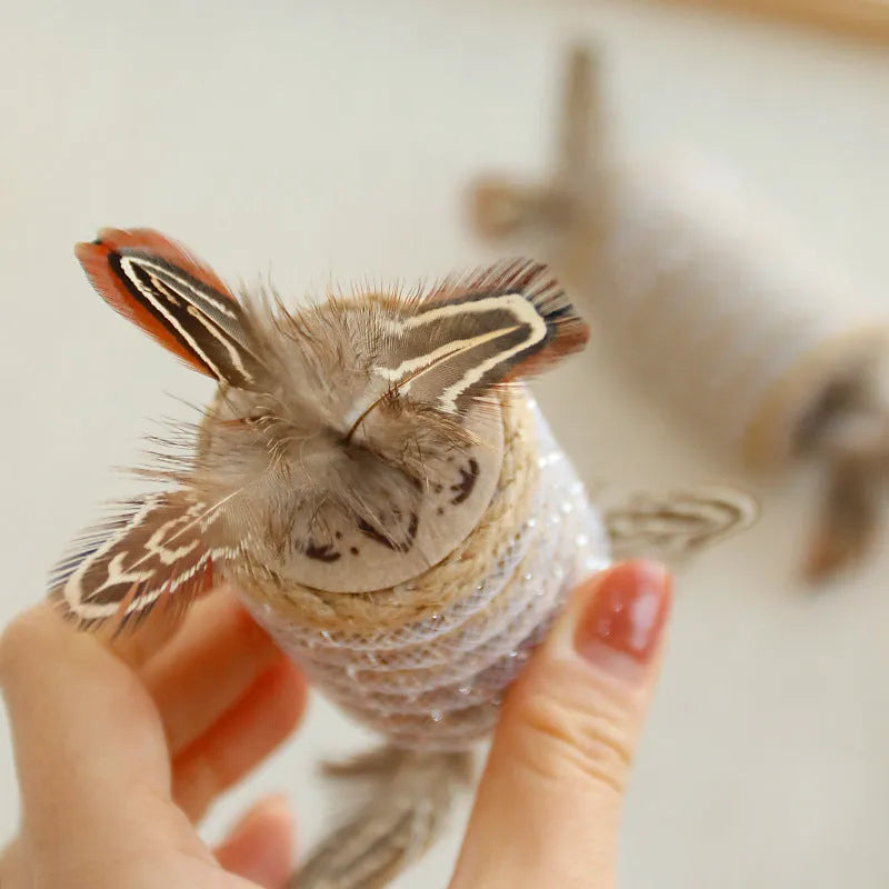 Beige cat toy with hemp rope, feathers, and a sound roller for scratching and interactive play.