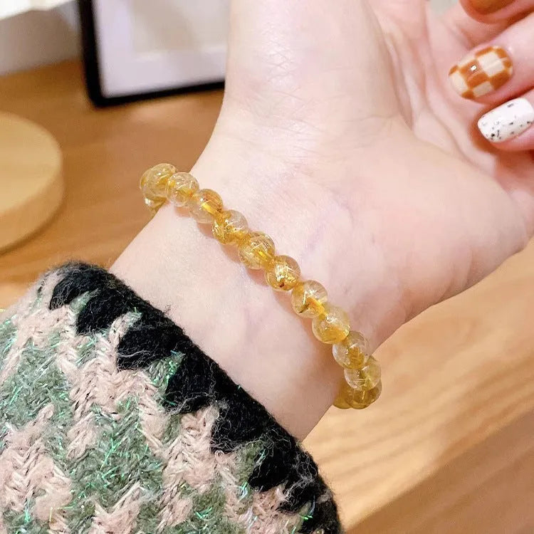 Gold rutilated quartz sunstone crystal bracelet with diamond-cut beads on wrist