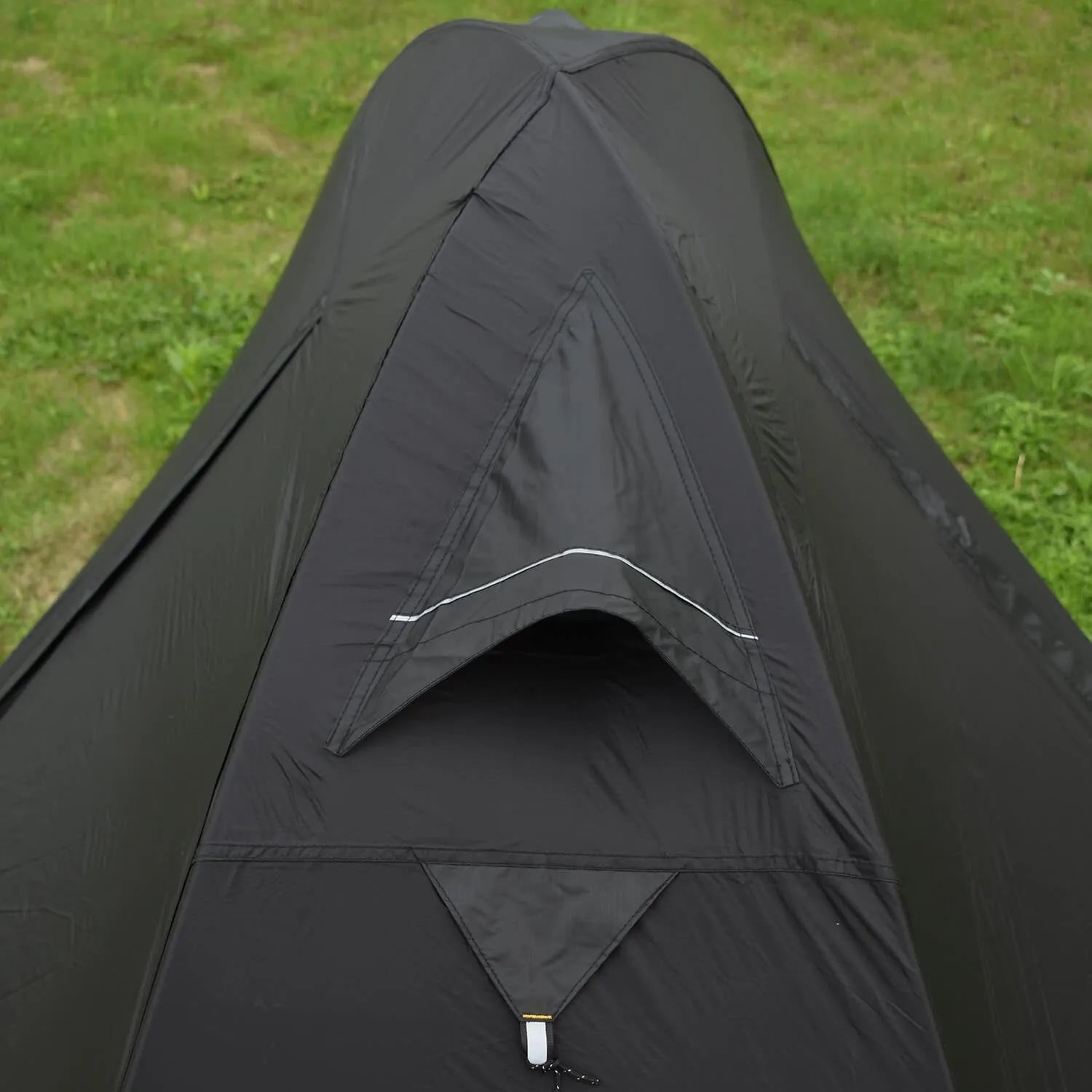 Single person green tunnel tent with aluminium poles pitched in a forest, showing mesh door and waterproof flysheet.