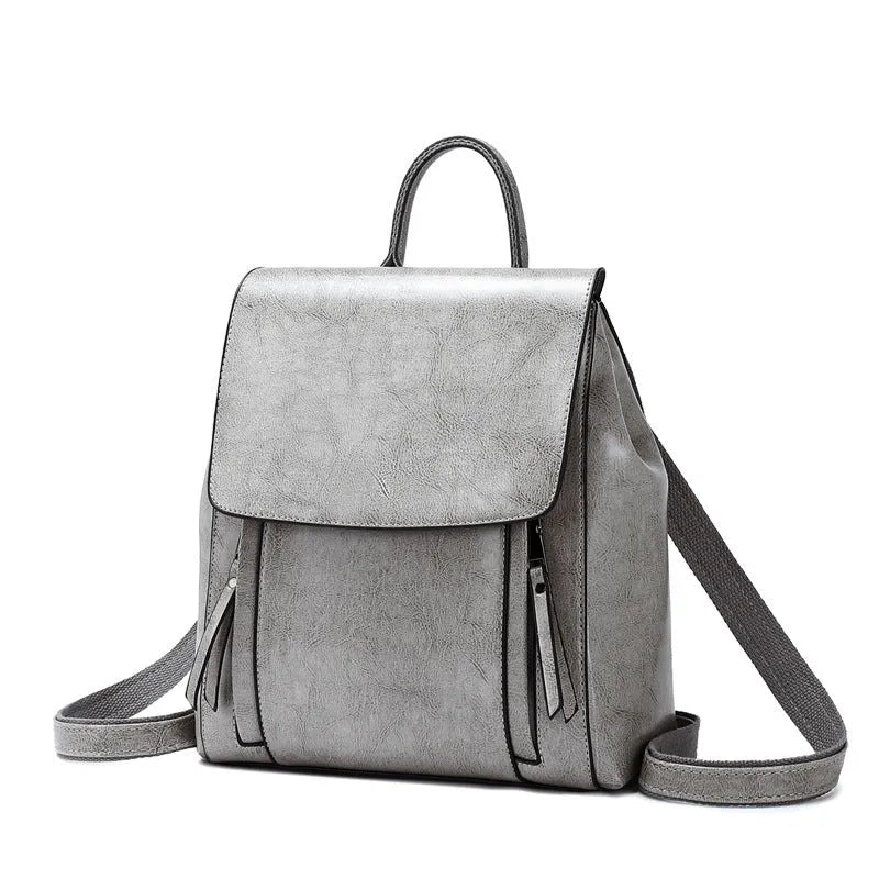 Soft black leather women's backpack with double straps, cover flap, and visible stitching, showing internal document and phone pockets.