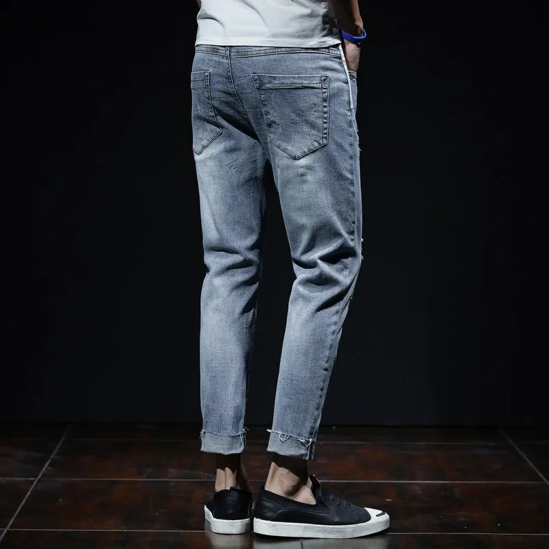 Light blue denim cropped jeans with ripped details on straight leg