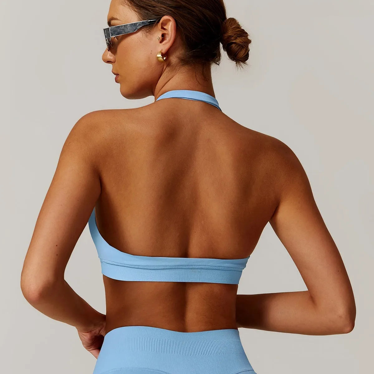 Women's halter-neck yoga bra in plum purple, showing hollow-back design and removable padding on a neutral background.