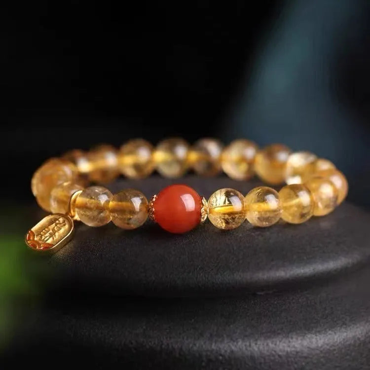 Natural red agate bead bracelet with gold-coloured spacers on a wrist.