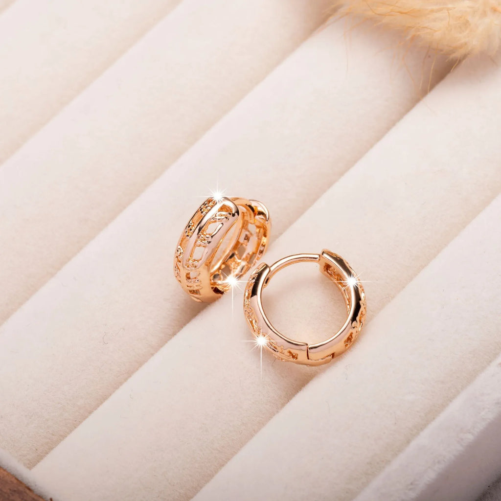 Rose gold hollowed-out heart and leaf shaped copper earrings on a white background, showing intricate cut-out details.