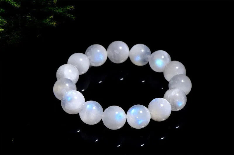 Natural white moonstone bracelet with round polished beads showing a blue sheen, laid flat.