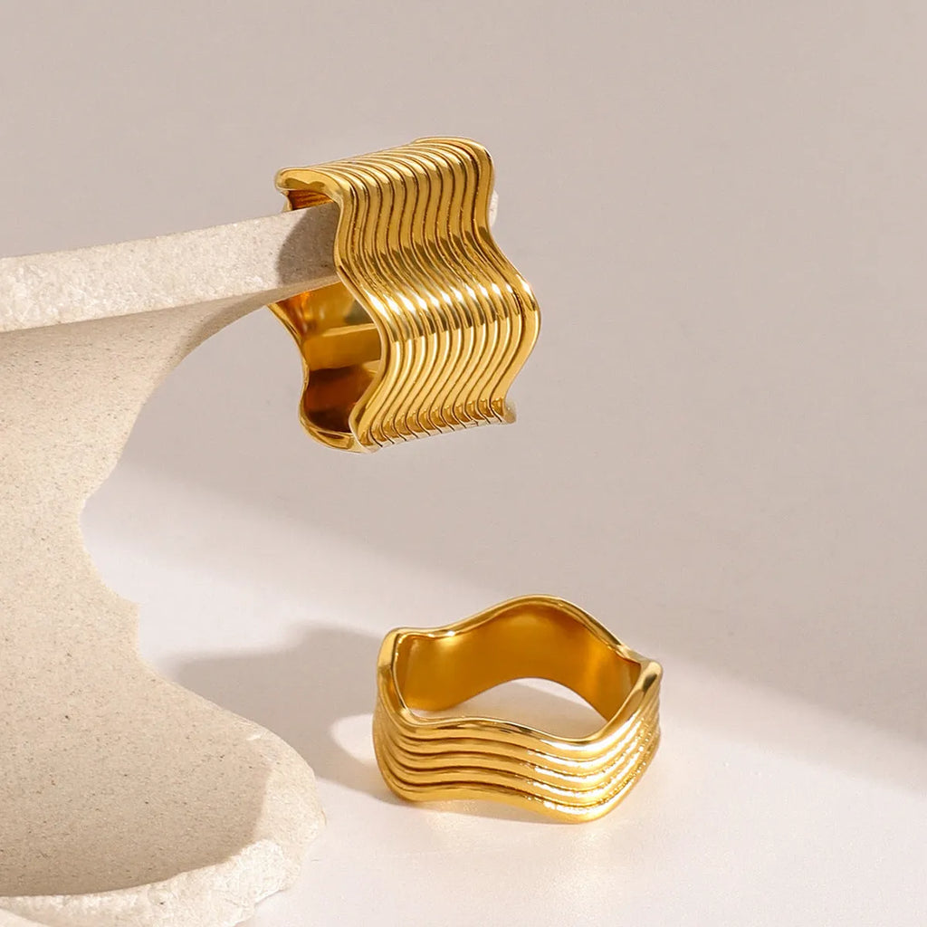 Stainless steel geometric wave ring with wide band and electroplated finish.