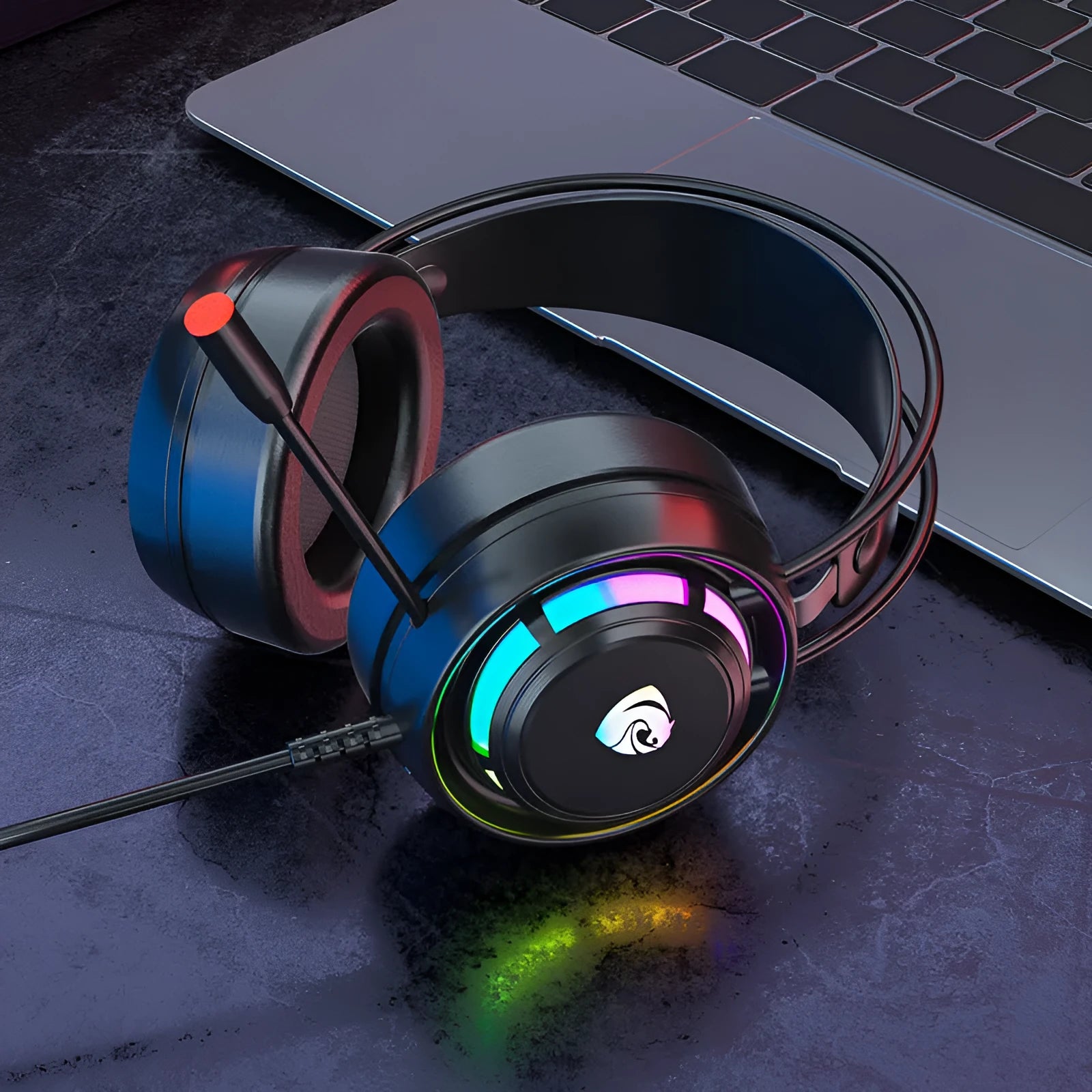 Black wired gaming headset with microphone, adjustable headband, and large circular ear cups on a desk.
