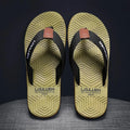 Men's black flip flops with open toe design and textured non-slip sole on a sandy beach.