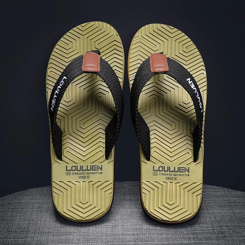 Men's black flip flops with open toe design and textured non-slip sole on a sandy beach.
