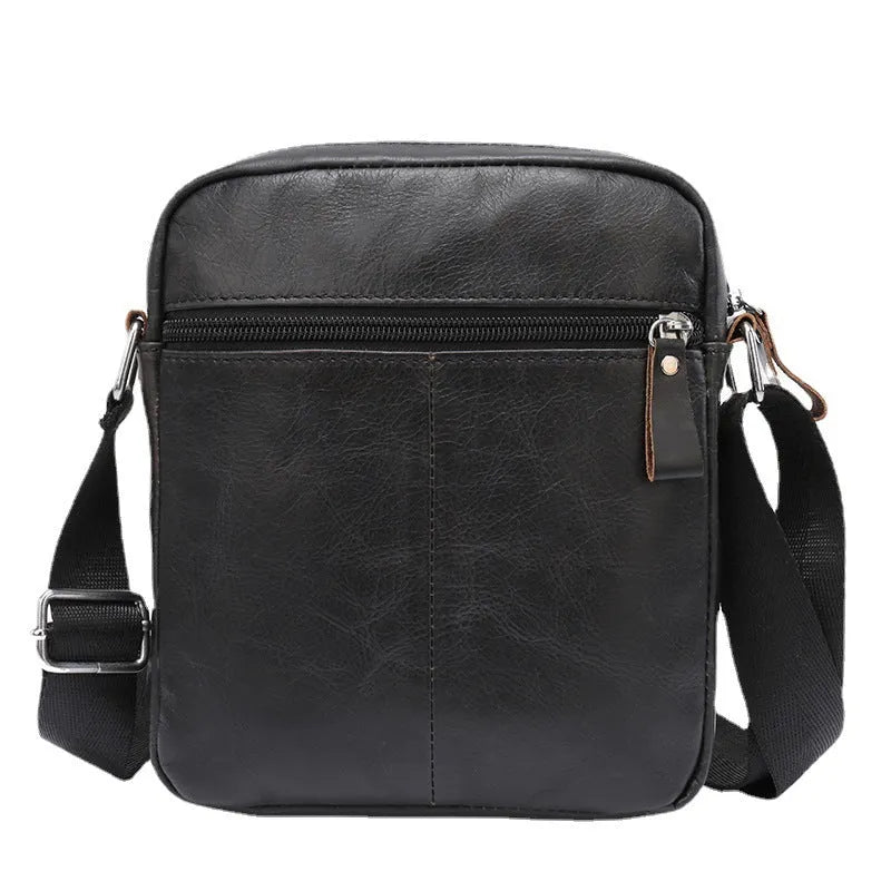 Retro brown leather messenger bag with crossbody strap on a table.
